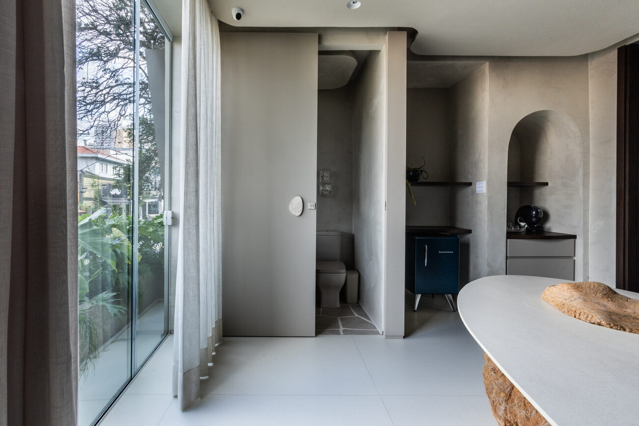 Sala de reuniões da Casa Palse com mesa escultural sobre pedra natural e vista de São Paulo